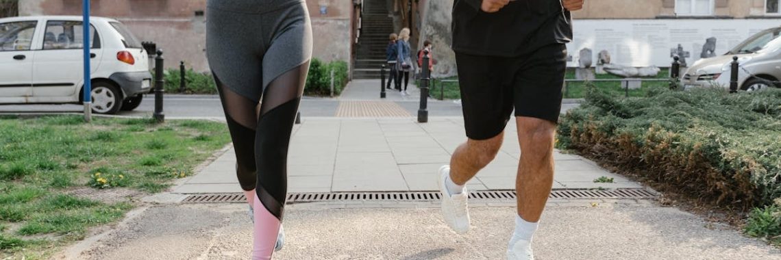 Fit couple jogging together on an urban sidewalk in sportswear.