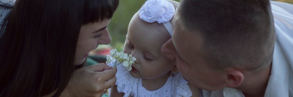 A loving family moment with parents and baby at a sunny outdoor picnic.